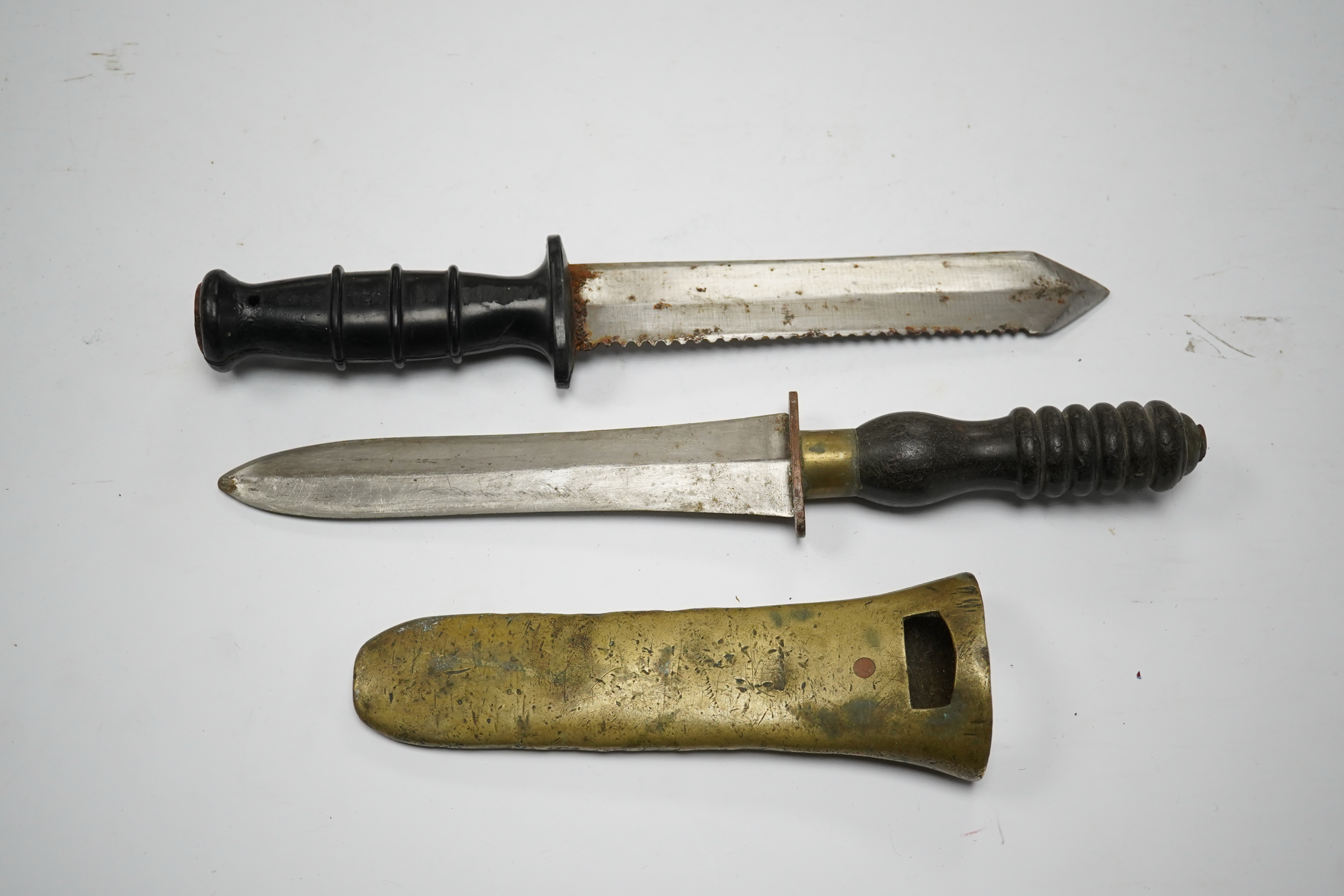 A Siebe Gorman & Co diving knife, regulation blade, turned wooden handle, brass cross piece with brass sheath, poor condition, together with another driver’s knife with sawback blade, etched John Noel and Sons, Sheffield